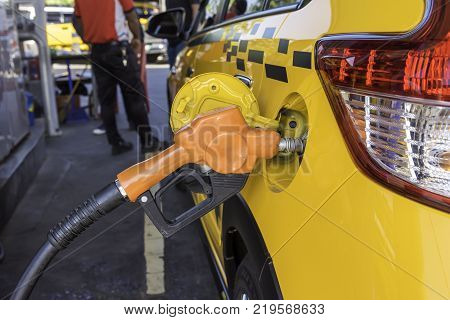 Yellow car is fueled by an orange Oil dispenser at the petrol pump.