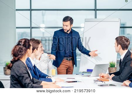Director of company having business meeting with his staff. showing presentation on flipchart or magnetic desk