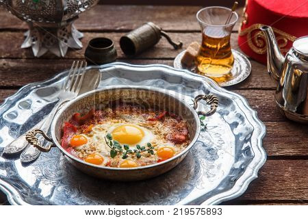 Copper pan with fried eggs and sausages, turkish style.