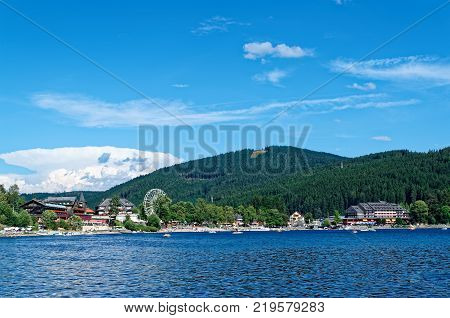 Traditional houses and ferris wheel on the promenade of the Titi lake (Titisee). Black Forest Germany