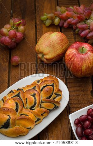 Still life of homemade pastries, sweet poppy pie on the background of fresh fruits, apples and grapes. Top View. Wooden rustic background
