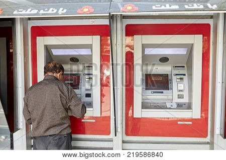 Yazd Iran - April 22 2017: An elderly Iranian man uses an ATM to withdraw cash from a national payment card of Iran.