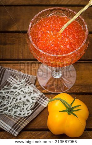 Red caviar in glass jar with gold spoon close up. Sea food. Healthy eating. Diet. Wooden rustic background. Top view. Selective focus