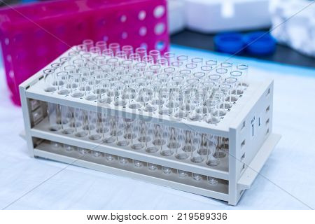 Chromatography fraction collector tubes on a rack holding 72 empty glass tubes on a lab bench as viewed from the right.