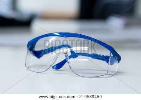 Close-up of blue safety goggles on a desk in a research lab.