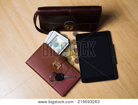 on a wooden table lay money notebook tablet handy bag and the keys to the car.
