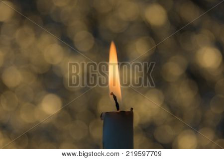 a candle burns, yellow, blue bokeh close-up