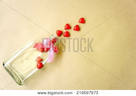 Minimal - Square bottle open with mini red hearts isolated on brown background. Copy space. Can use for medical or candy.