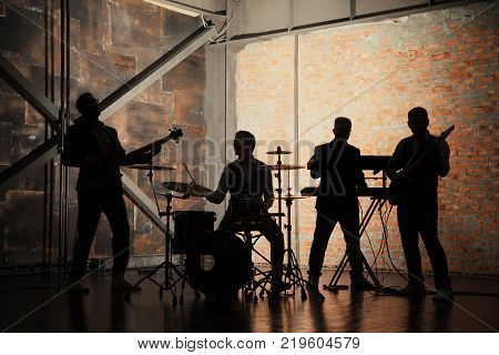 Bands silhouettes with on a concert. Music band and fashion. Handsome young men in suits playing rock and singing song.