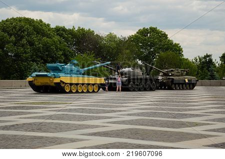 KYIV, UKRAINE - JUNE 1, 2017, Young family making photo on the one of three panzers standing on the Motherlands square in Kyiv. One of the panzers is painted in national Ukrainians colours