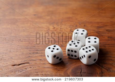 Game of chance concept. Gambling devices. White dice on rustic wooden board. Copy space for text.