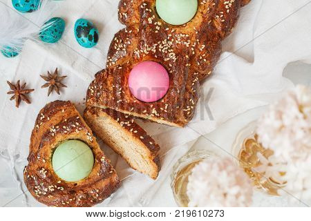 Traditional Greek Easter bread - tsoureki sliced in Easter decoration with painted eggs and flowers. Easter Festival concept.