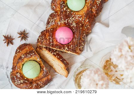 Traditional Greek Easter bread - tsoureki sliced in Easter decoration with painted eggs and flowers. Easter Festival concept.