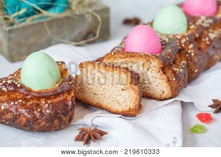 Traditional Greek Easter bread - tsoureki sliced in Easter decoration with painted eggs and flowers. Easter Festival concept.
