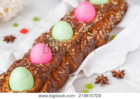Traditional Greek Easter bread - tsoureki in Easter decorations with painted eggs and flowers. Easter Festival concept.