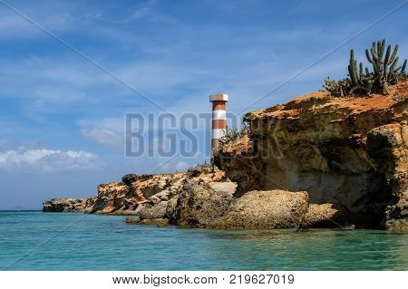 Travel photography - seascape with a light house and cactus sailing along the coast of Cubagua island (Venezuela):