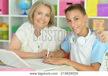Sad granny with her grandson using laptop at home