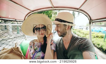 Young handsome man in hat with his girlfriend on traditional thai bus songteo . Couple travel Thailand during their honeymoon