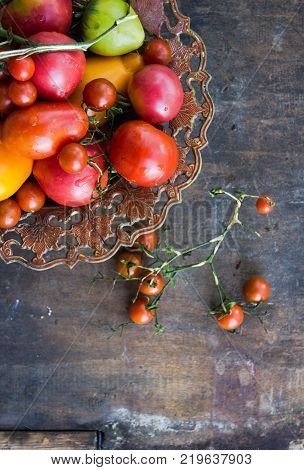 Cherry tomatoes in a copper bowl. Colorful tomatoes Tomatoes background. Fresh tomatoes Healthy food concept. Colorful festive still life. Loosely laid tomatoes in different positions. Copyspace