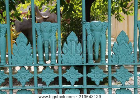 Elephant themed fence in front of elephant statues.