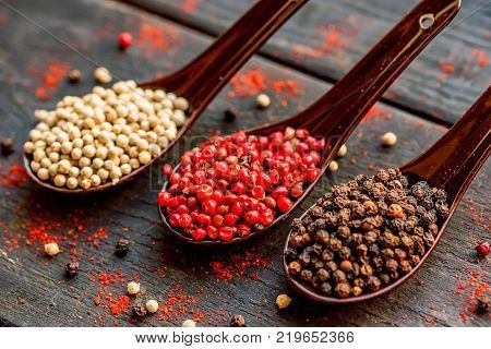 Close up studio shot of assorted peppercorn in spoons on dark background