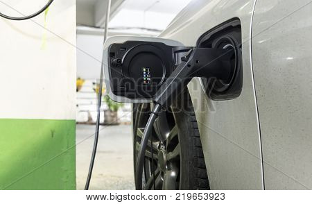 Charging an electric car with the power cable supply plugged in car park.