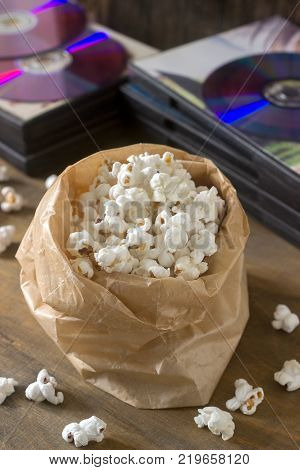Pop corn and laser discs on a wooden surface. Rustic style, selective focus.