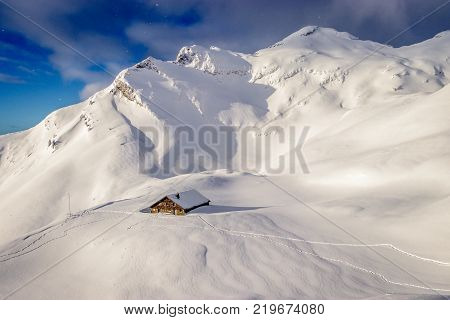 Early morning sun breaking through over a fantastic mountain landscape covered with a lot fresh snow. On the left of the picture the 