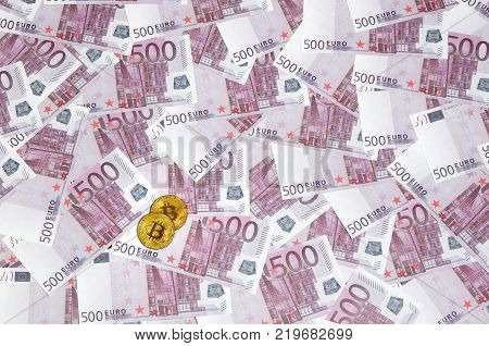 Bitcoins over pile of five hundred euro banknotes. Traditional money versus cryptocurrency concept. Gold coin above 500 euro bills. Close up