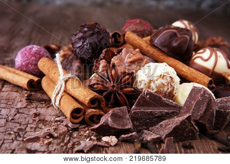 A selection of assorted chocolate truffle pralines on a wooden table with dark chocolate cinnamon and anise.