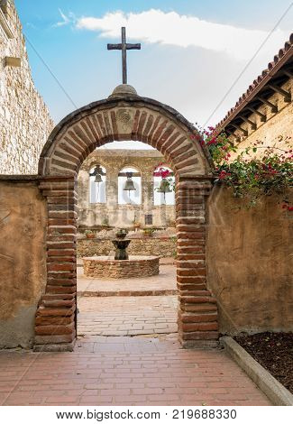 Bells in bell tower surround paved patio at San Juan Capistrano mission