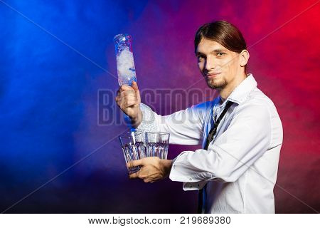 Alcohol liquor party relax flair bartending concept. Barman with bottle and glasses. Youthful tapster on colorful background.