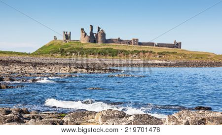The coast of Northumberland, in northern England, between the villages of Craster and Embleton. Dunstanburgh Castle, a 14th-century fortification, can be seen in the background.