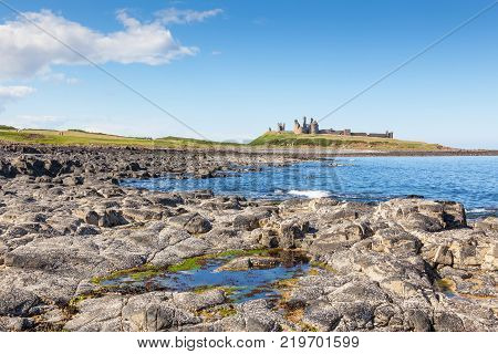 The coast of Northumberland, in northern England, between the villages of Craster and Embleton. Dunstanburgh Castle, a 14th-century fortification, can be seen in the background.