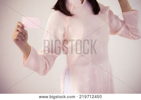 beautiful woman in pink dress and vietnam hat holding business card.