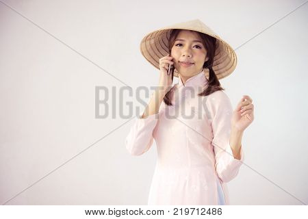 beautiful woman in pink dress and vietnam hat holding smartphone.