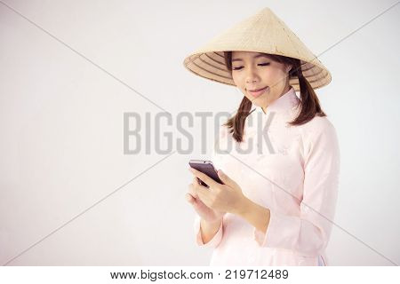 beautiful woman in pink dress and vietnam hat holding smartphone.
