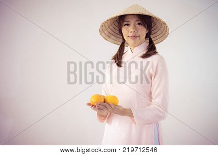 beautiful woman in pink dress and vietnam hat holding orange