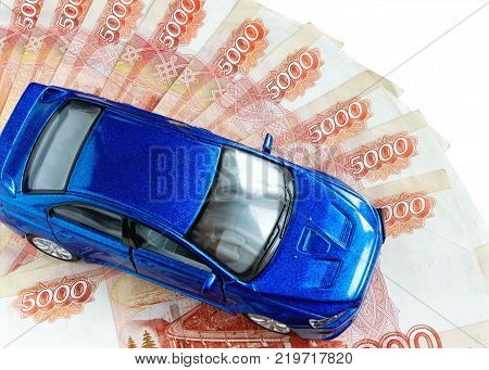 The toy car of blue color costs on five-thousandth ruble notes. Top view. On a white background. Indoors. Color. Horizontal format. Photo.