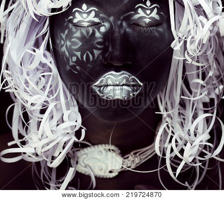 creative makeup like Ethiopian mask, white pattern on black face close up, halloween horror