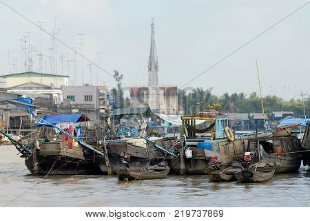 CAI BE, VIETNAM - FEBRUARY 16, 2007: View to the boats floating on water with the church at the background in Cai Be, Vietnam. Cai Be is often called Venice of Indochina.