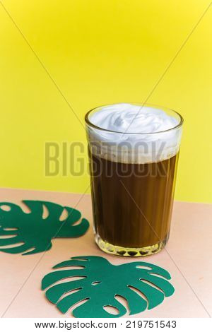 iced coffee and green paper leaves monstera bright yellow orange pastel background