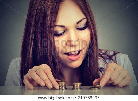 Young woman counting money stacking up coins