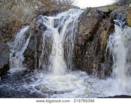 Waterfall From The Thawed Waters. Melting Snow In The Hilly Tundra. Waterfall