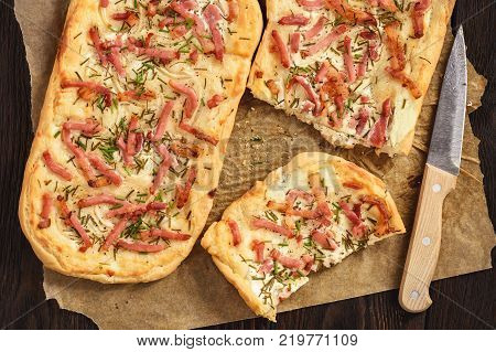 Tarte flambee, traditional alsatian pizza on wooden background.