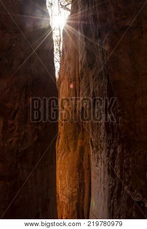 Sunbeams shining through the crevice in the red loamy wall of Providence Canyon in sunny day USA