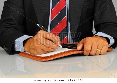 Közelkép az íróasztalánál ül, és írásban notebook üzletember. Vízszintes formátum, amely csak 
