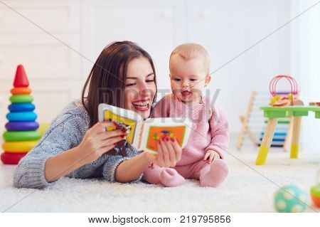 cute mother and daughter playing together reading first book