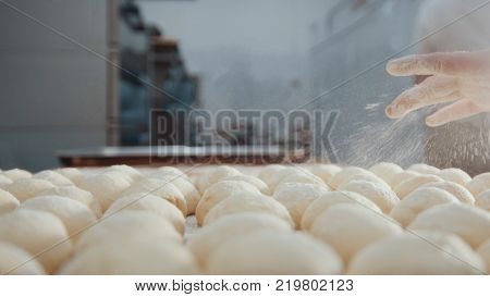 Cook sifts flour and shugar decorating pies in the bakery, close-up