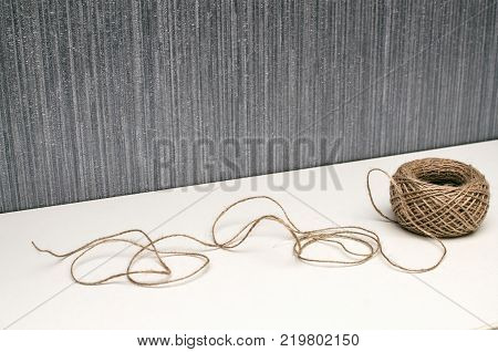 Jute rope lying on the table on the silver wall background.